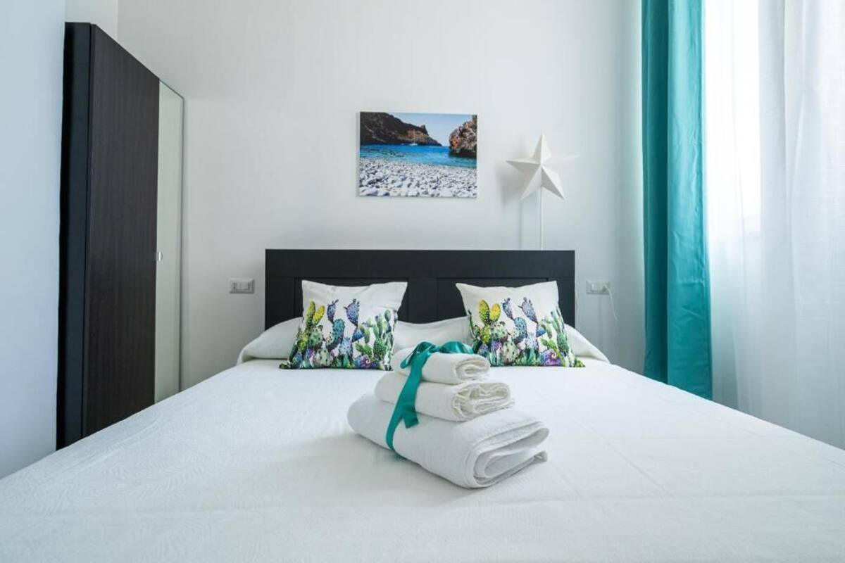 Una habitación de hotel con cama, almohadas, una lámpara con forma de estrella y una pintura de una playa.