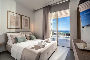 Ein modernes Hotelzimmer mit Bett, einem Balkon mit Blick und einem Fernseher an der Wand.