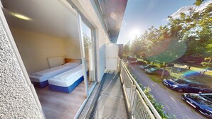 A balcony with a bed, a view of parked cars, and a clear sky. - Tunici Team Hotel (Hamburg)