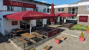 A TUNICI TEAM HOTEL with outdoor seating, red umbrellas, and potted plants. - Tunici Team Hotel (Hamburg)