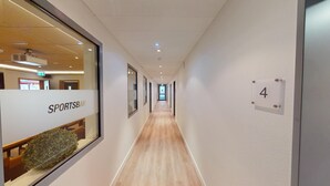 A hallway with a Sportsbar sign, a wooden floor, and a number 4 sign on the wall. - Tunici Team Hotel (Hamburg)