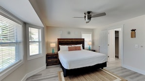 A bedroom with a large bed, a ceiling fan, and a view through the window. - Turtle Dove | Five Min Walk to Beach, Large Fenced Yard (Panama City)