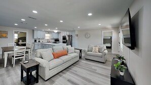 A modern living room with a sofa, a coffee table, and a TV mounted on the wall. - Turtle Dove | Five Min Walk to Beach, Large Fenced Yard (Panama City)