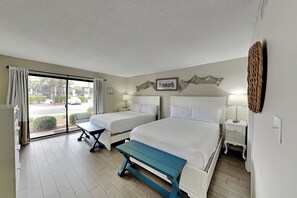 Ett hotellrum med två sängar, en bänk, utsikt över gatan och en vägg med en dekorativ skylt.