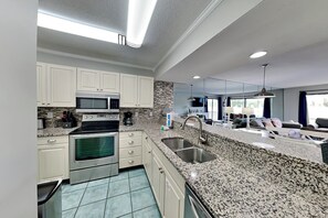 Eine moderne Küche mit Granit Arbeitsplatten, Edelstahlgeräten und einer großen Kücheninsel mit Spüle.