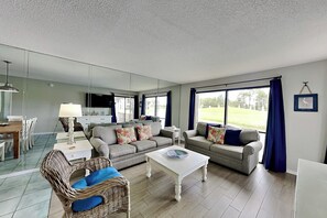 Ein modernes Wohnzimmer mit Essbereich, großen Fenstern und einem Flachbildfernseher.