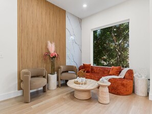 Una sala moderna con un sofá, dos sillones, una mesita de centro y un panel de pared de madera.