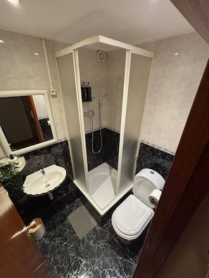 Ein Badezimmer mit Duschkabine, Waschbecken und Toilette.