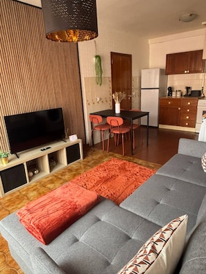 Ein modernes Wohnzimmer mit einer Couch, Fernseher und Essbereich.