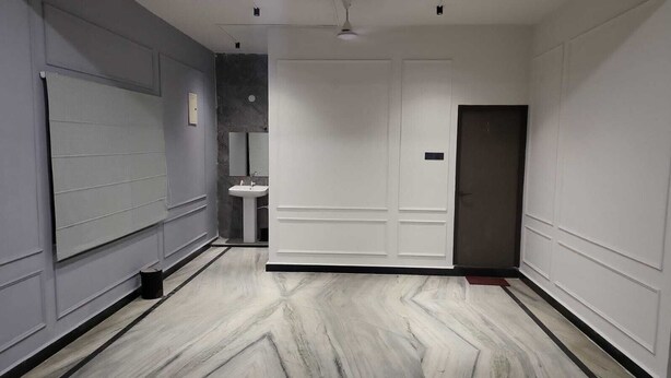 Un couloir avec une porte blanche, un lavabo et un miroir.