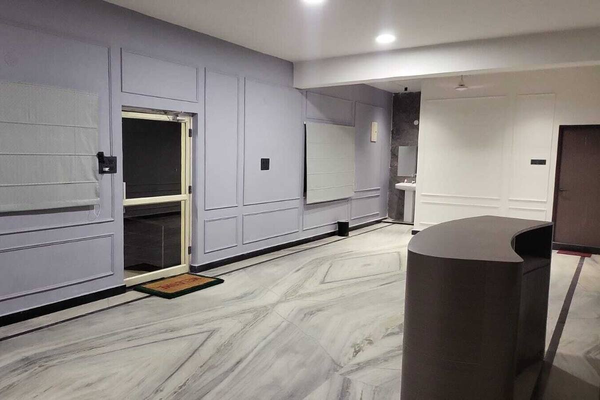 A hallway with a reception desk, a door with a glass panel, and a doormat.