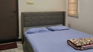 Une chambre à coucher avec un lit, un climatiseur, une porte et une fenêtre avec des stores.