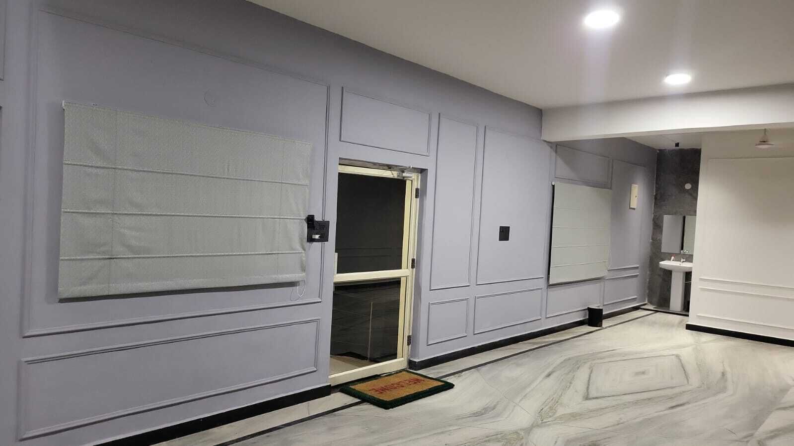 A hallway with a door, a small window, and a light fixture.