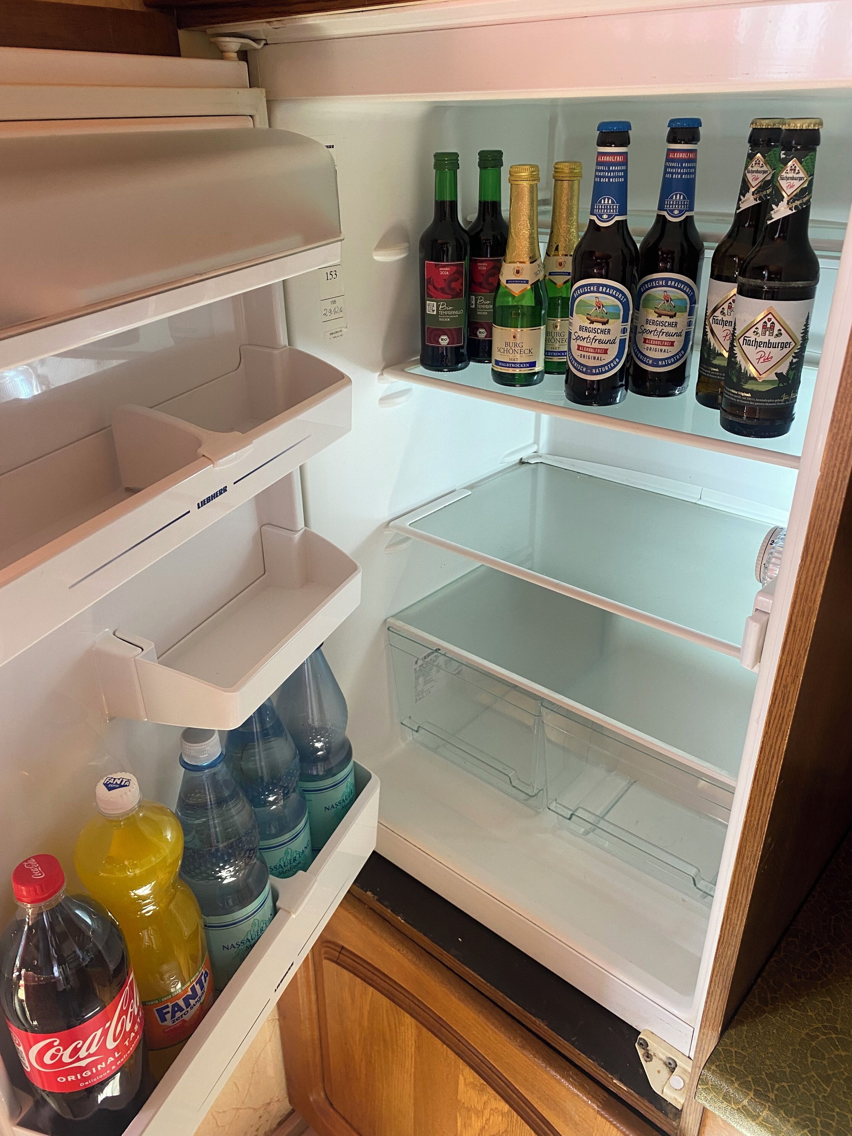A refrigerator with multiple shelves, some containing bottles of beverages and others empty.