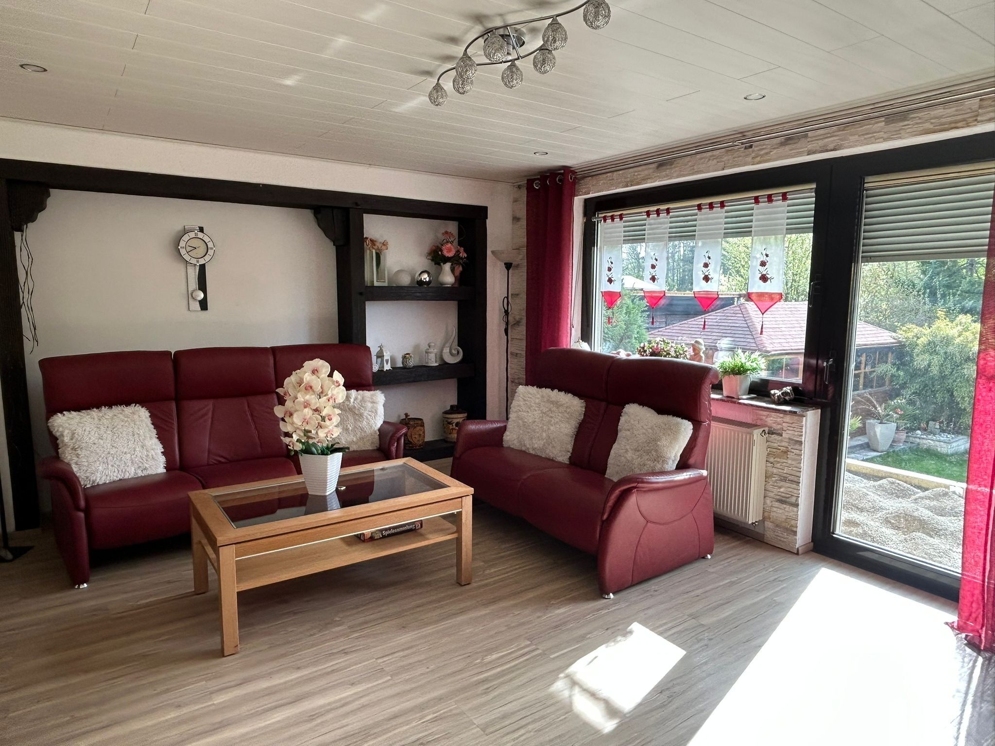 A living room with a red sofa, a wooden coffee table, and a bookshelf.