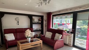 En stue med en rød sofa, et træbord og en reol.