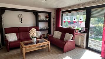 A living room with a red sofa, a wooden coffee table, and a bookshelf.