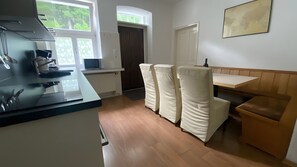 Et køkken med komfur, mikrobølgeovn samt et spiseområde med bænk og stole.