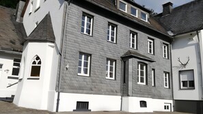 En flereret bygning med en symmetrisk facade, store vinduer og et markant buet vindue i stueetagen.