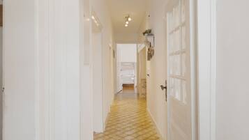 A hallway with white doors, a tiled floor, and a bed in the distance.