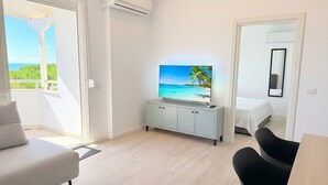 Una habitación de hotel moderna con balcón, televisión de pantalla plana, cama y zona de comedor.
