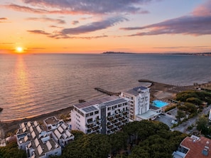 A coastal hotel with multiple floors, a swimming pool, and a pier extending into the sea. - Sea Breeze Apartment with Balcony (Durres)