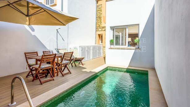 Un espace aménagé au bord de la piscine avec une table et des chaises, une petite piscine et un bâtiment doté d’une fenêtre.