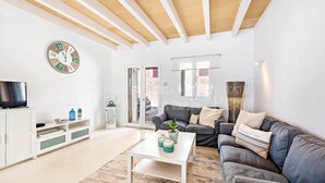 Un salon moderne avec un meuble de rangement blanc pour les appareils multimédias, un canapé gris, une table basse blanche et un plafond en bois.