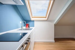 A modern kitchen with a skylight, white cabinets, and a wooden floor. - Casalina by Napoliapartments (Naples)