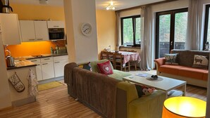 Ein gemütliches Wohnzimmer mit einer Couch, einem Esstisch und einer Küchenzeile mit Schränken und einer Mikrowelle.