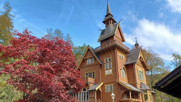 Ein traditionelles Holzgebäude mit einem markanten Turm und zahlreichen Fenstern.