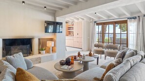 A spacious living room with a fireplace, comfortable seating, a television, and a view of the outdoors. - Vacation home Prana by Interhome (Moraira)