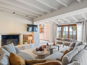 A spacious living room with a fireplace, comfortable seating, a television, and a view of the outdoors. - Vacation home Prana by Interhome (Moraira)