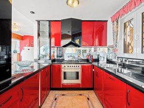 A modern kitchen with red cabinets, a central island, and a large window. - Horizonte by Interhome (Benissa)