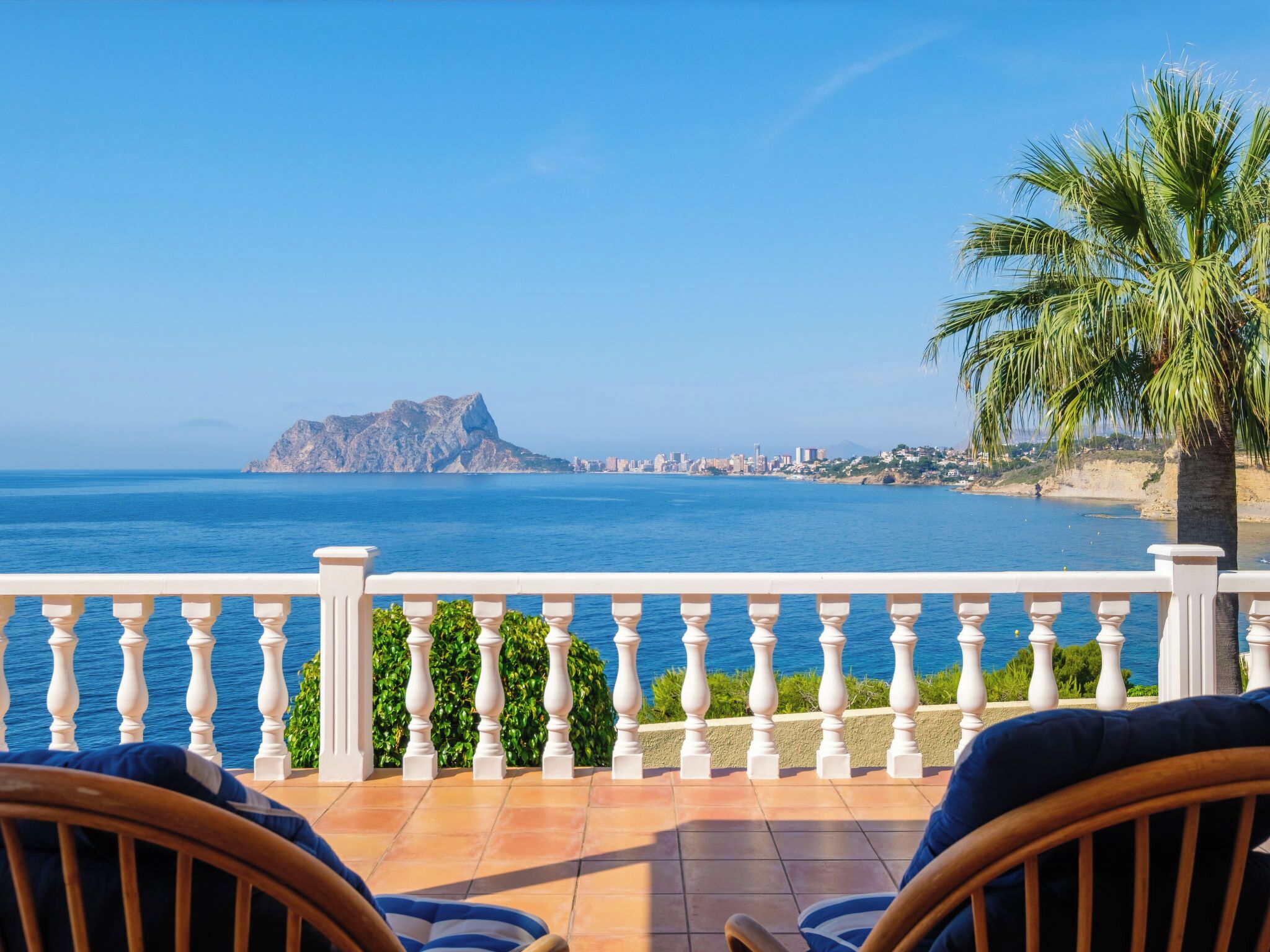 A balcony with a view of the sea and a distant island.