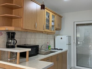 Eine Küche mit Holzausstattung, einer Kaffeemaschine, einem Herd und einem Kühlschrank.
