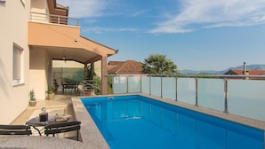 Un edificio residencial con piscina, mobiliario de exterior y vistas a las montañas.