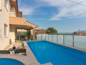A residential building with a swimming pool, outdoor seating, and a view of the mountains. - Holiday Home Vele With Pool (Vrgorac)
