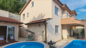 Una casa de dos pisos con piscina, balcón y patio amoblado.