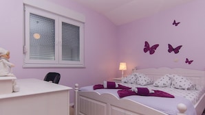 Un dormitorio con cama, escritorio, silla, ventana con persianas y adornos en la pared.