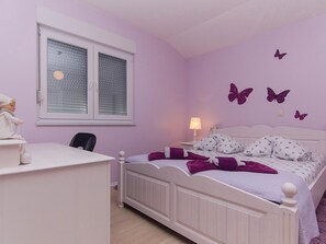 A bedroom with a bed, a desk, a chair, a window with blinds, and wall decorations. - Holiday Home Vele With Pool (Vrgorac)