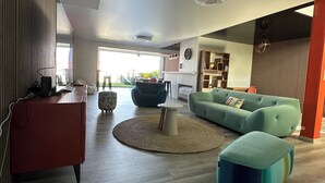 Un salon moderne avec un canapé, un pouf et une table basse ronde.