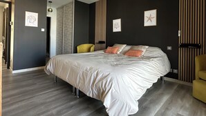 Une chambre moderne avec un grand lit, un ventilateur de plafond et un mur foncé à rayures verticales.