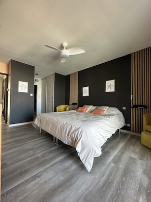 Ein modernes Schlafzimmer mit einem großen Bett, einem Deckenventilator und einer dunklen Wand mit vertikalen Streifen.