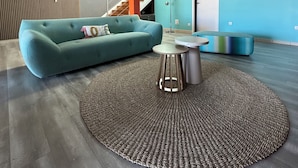 Un salon moderne avec un canapé de couleur turquoise, une table basse ronde et un tapis à motifs.