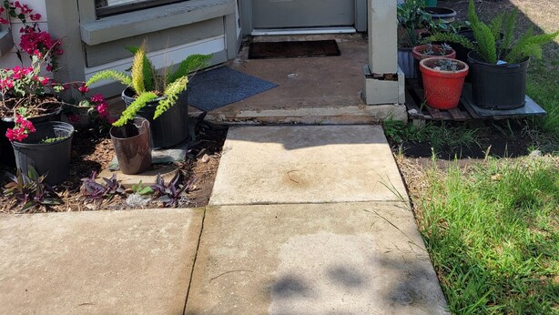A house with a closed grey door, a porch with potted plants, a wooden fence, and a green trash bin. - Wonderful 3-bedroom house with AC in charming San Antonio (San Antonio)