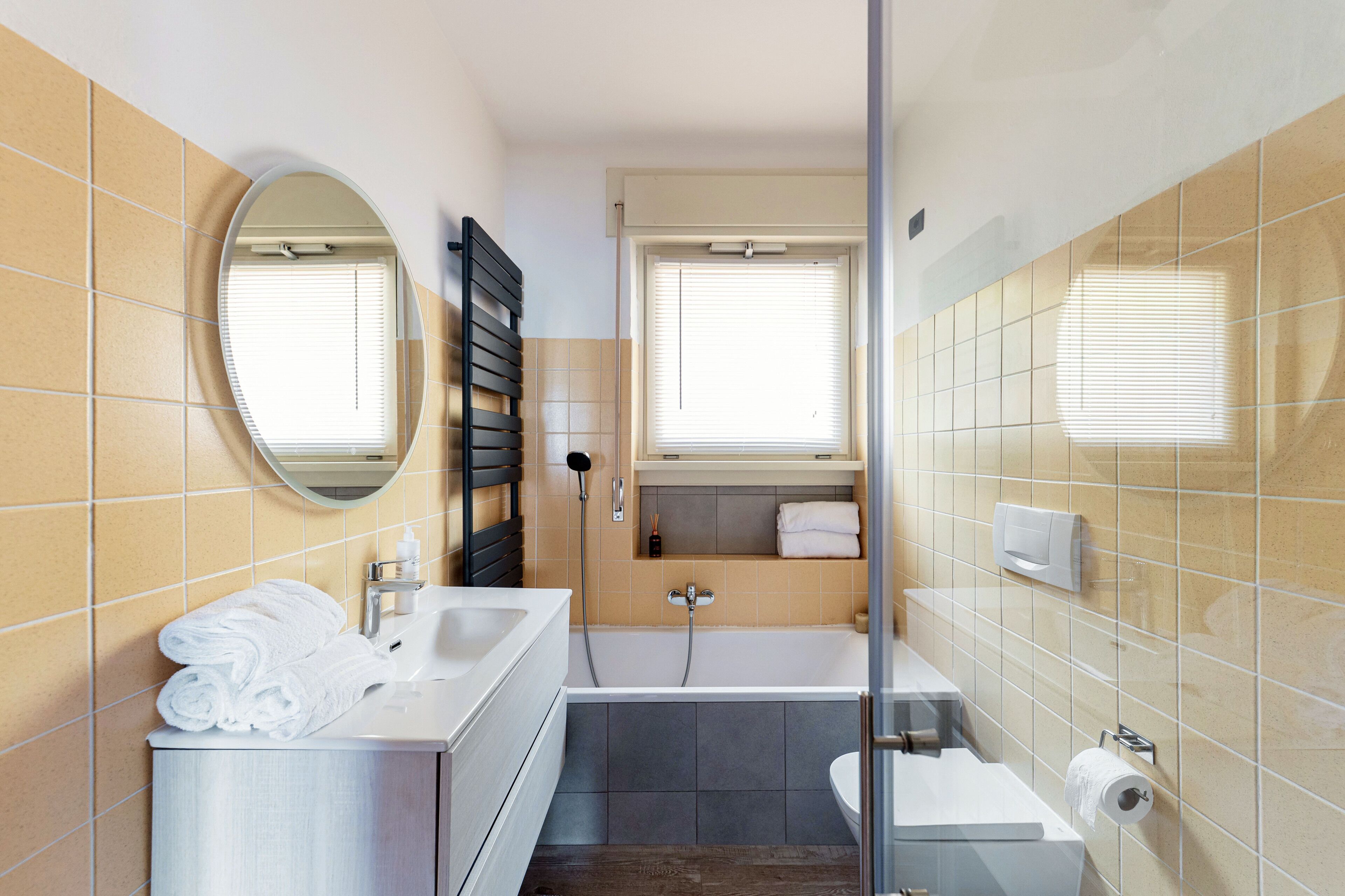 Ein modernes Badezimmer mit Waschbecken, Spiegel, Handtuchhalter, Dusche und Toilette.