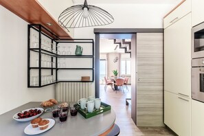 Una cocina moderna con un espacio para vinos integrado, un comedor con mesa y sillas, y vista a una sala de estar.