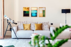 Una sala de estar con un sofá, un telescopio y arte abstracto en la pared.