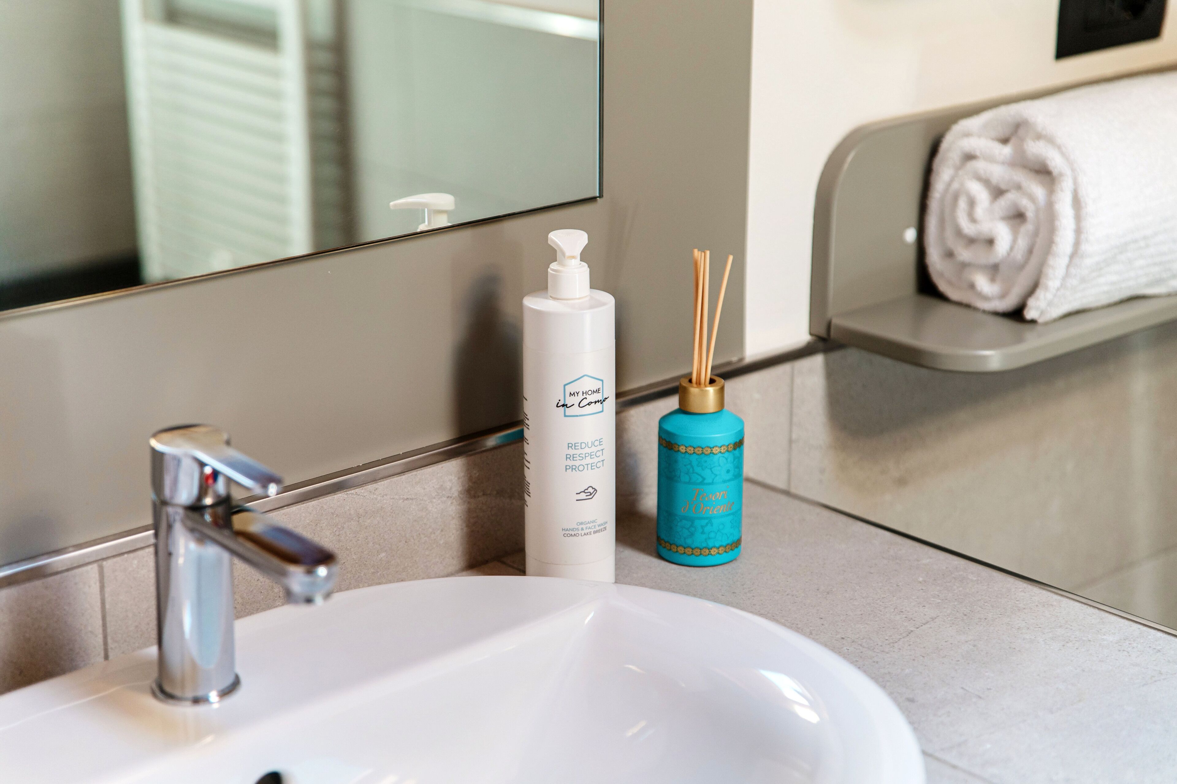 A bathroom sink with a mirror, a white bottle, and a blue bottle.